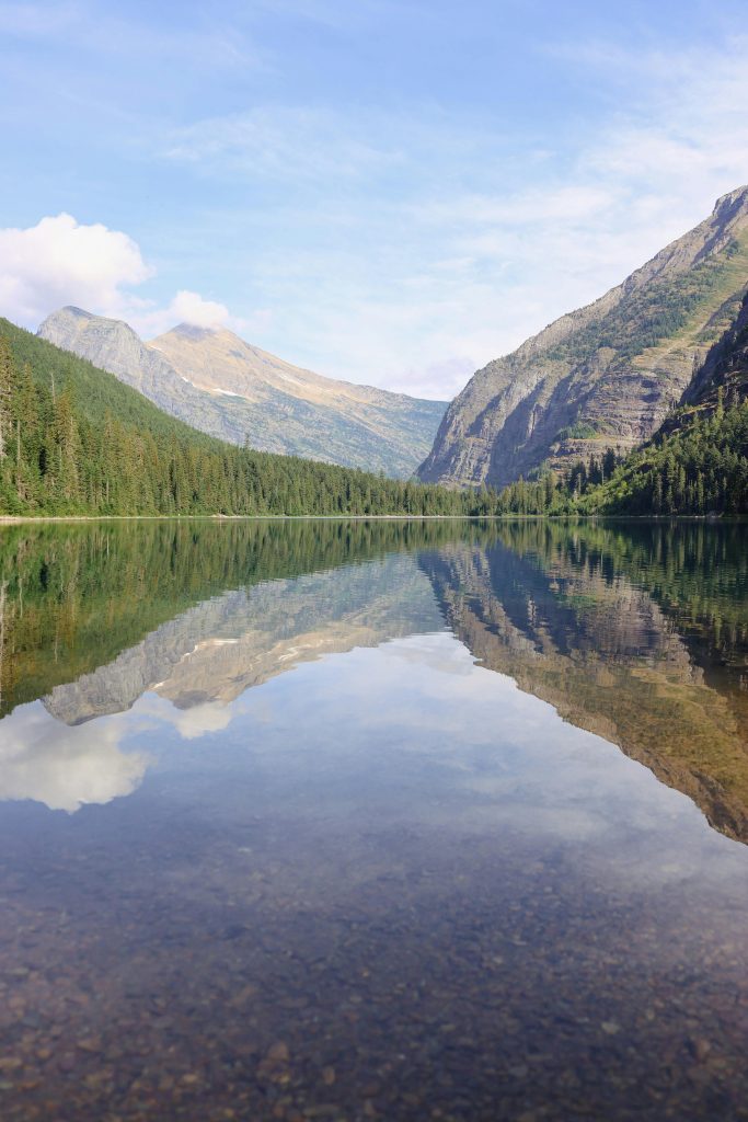 Serene mountain lake with clear reflections in Glacier National Park, Montana.