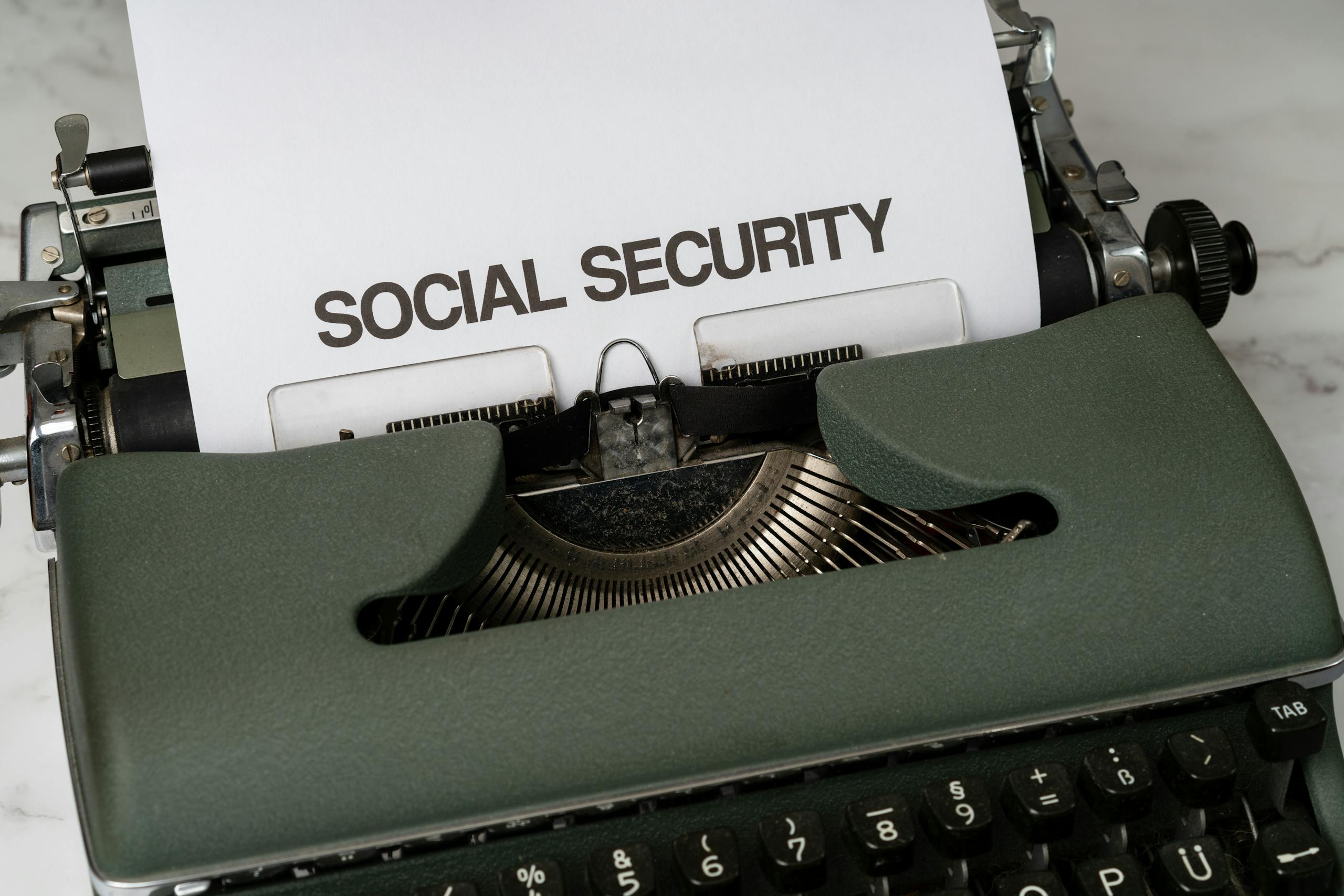 Close-up of a vintage typewriter typing 'SOCIAL SECURITY' on paper.